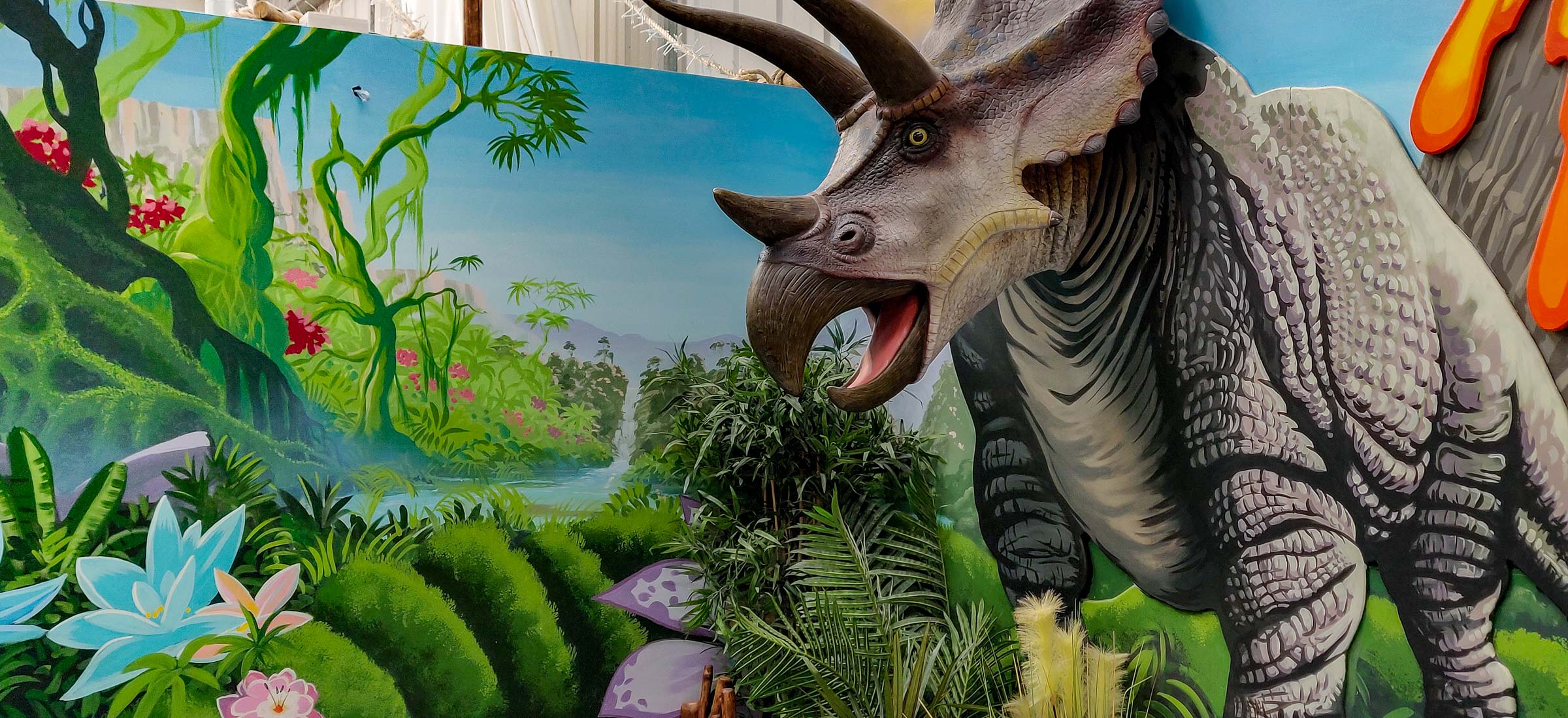 Very life-like triceratops looms out of the dinosaur mural